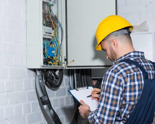 Professional electrician inspecting wires in electrical box